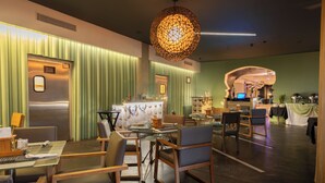 A modern hotel lobby with a reception desk, seating area, and a large decorative light fixture. - Riande Urban Hotel (Panama City)