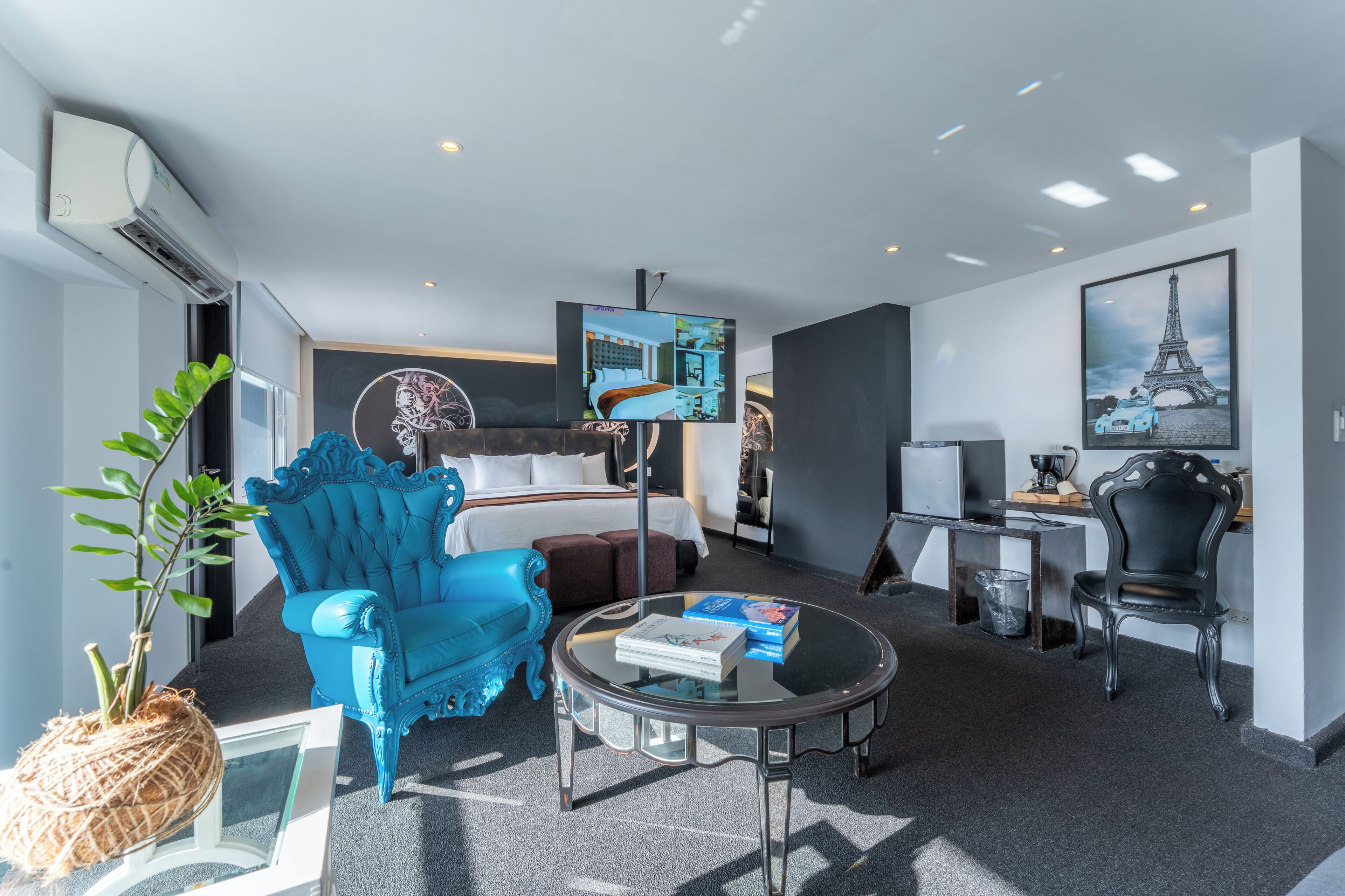 Habitación de hotel con cama, televisor, cafetera, escritorio y silla.