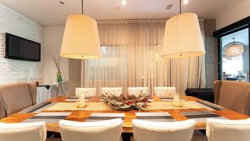 Comedor con mesa de madera, sillas blancas y dos lámparas colgantes.