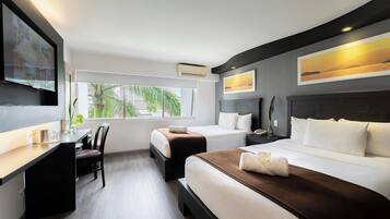Una habitación de hotel con cama, mesita de noche, silla, escritorio y un ventanal grande.
