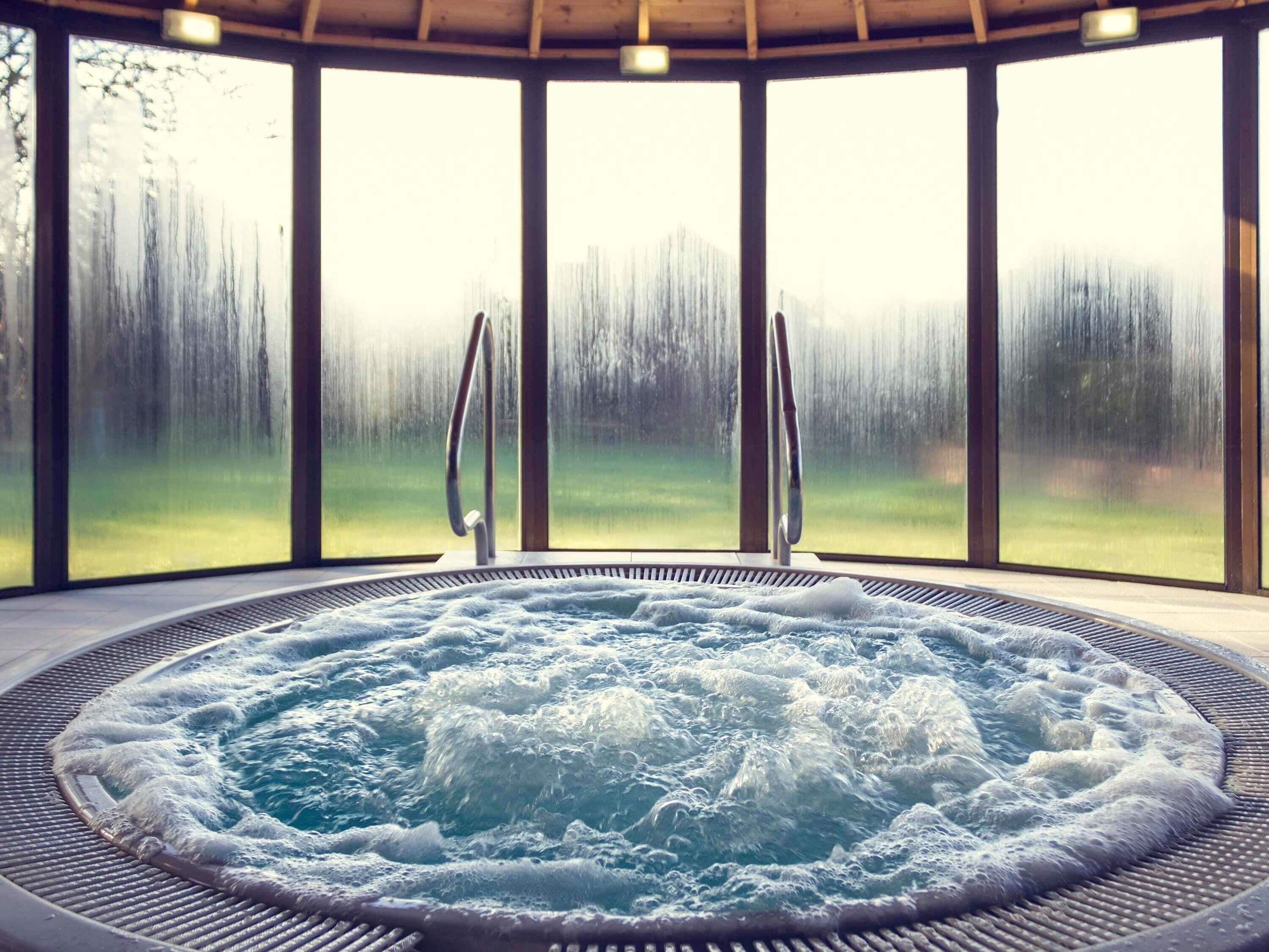 Ein Whirlpool mit Blick auf einen Wald durch große Fenster.