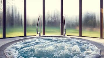 Ein Whirlpool mit Blick auf einen Wald durch große Fenster.