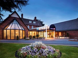 A hotel with a traditional brick facade, a glass conservatory, and a modern annex.