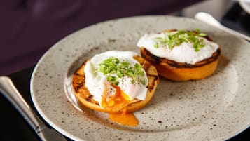 A plate with two poached eggs on toast, garnished with greens, on a speckled ceramic plate.