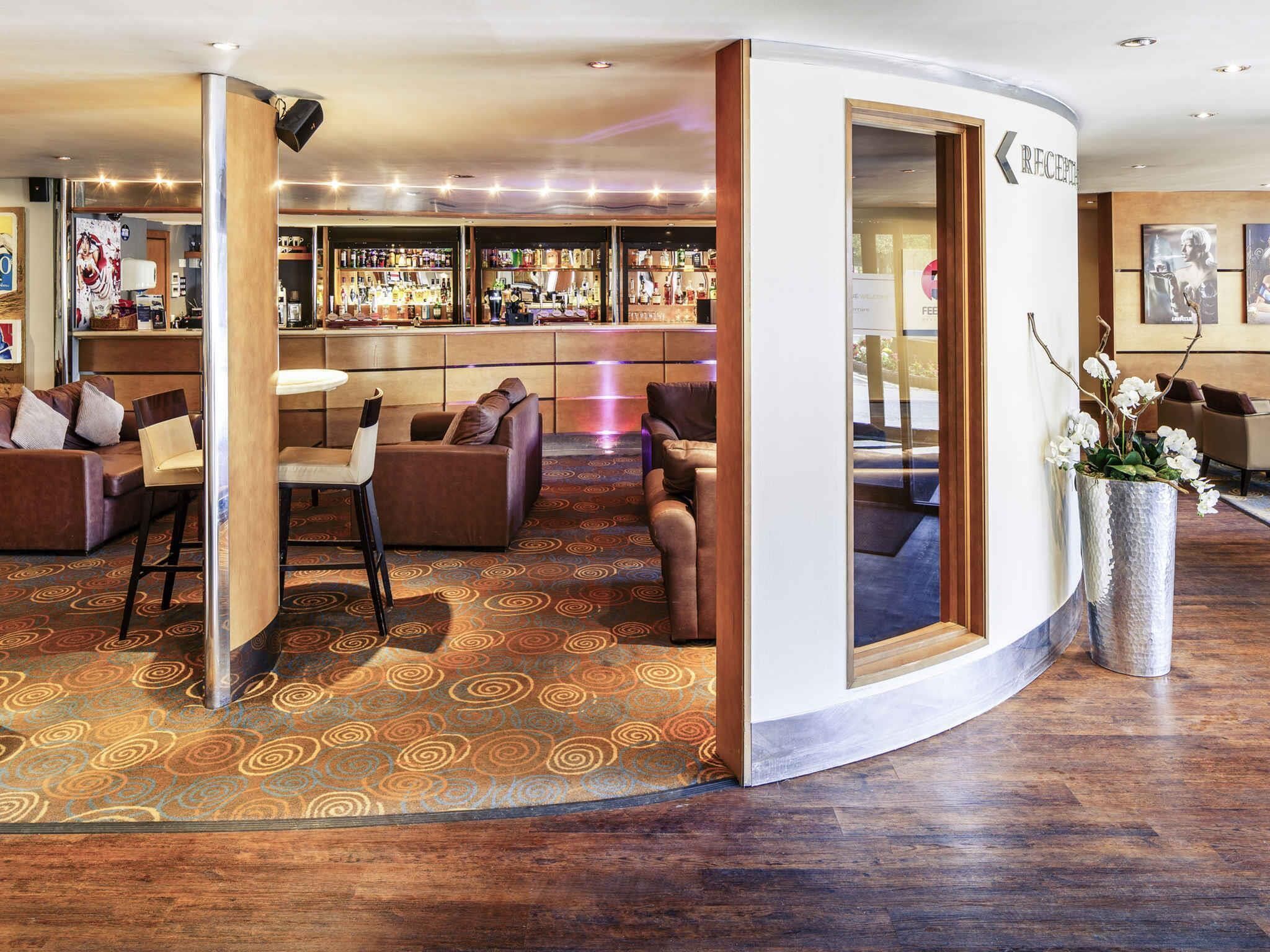 Una hall d'albergo con area bar, posti a sedere e reception.