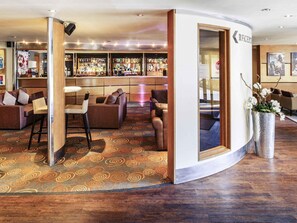 Un vestíbulo de hotel con zona de bar, asientos y mostrador de recepción.