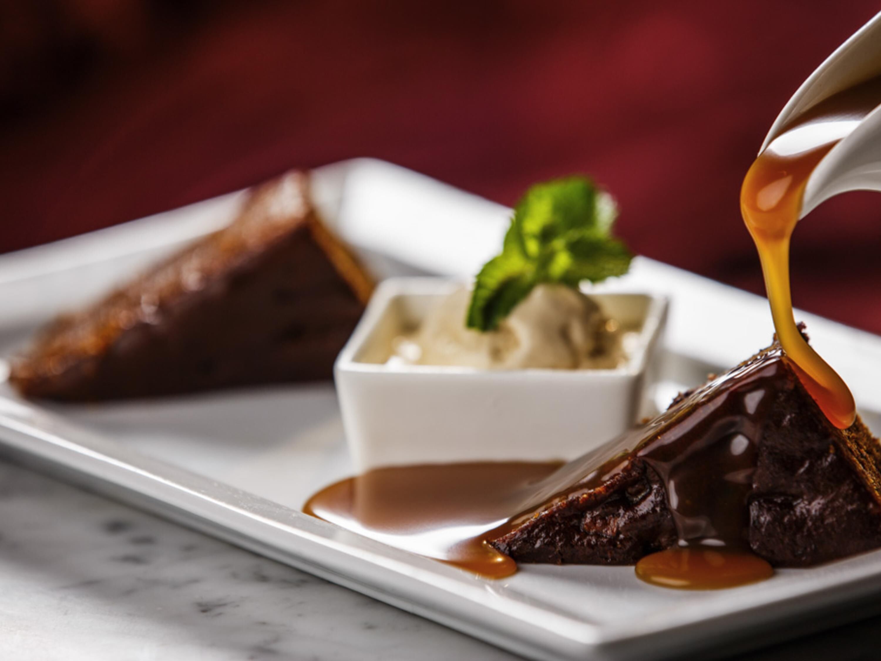 Un plato de postre con un pastel volcán de chocolate, helado y una ramita de menta.