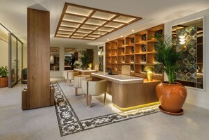 A modern reception area with a wooden reception desk, seating, and a patterned wall.