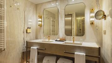 Un baño moderno con paredes de mármol, lavamanos dobles y un espejo grande.