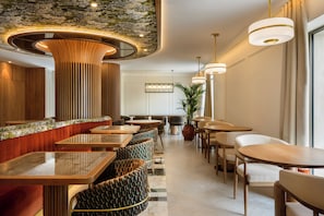 Een modern interieur met een lange toonbank, verschillende zithoeken en hanglampen.