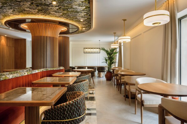 Un intérieur moderne avec un long comptoir, de nombreux espaces de détente et des luminaires suspendus.