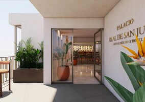 Una entrada de hotel moderna con puerta de vidrio, un área de bar visible a través de la puerta, y un letrero que dice "Palacio Real de San Juan".