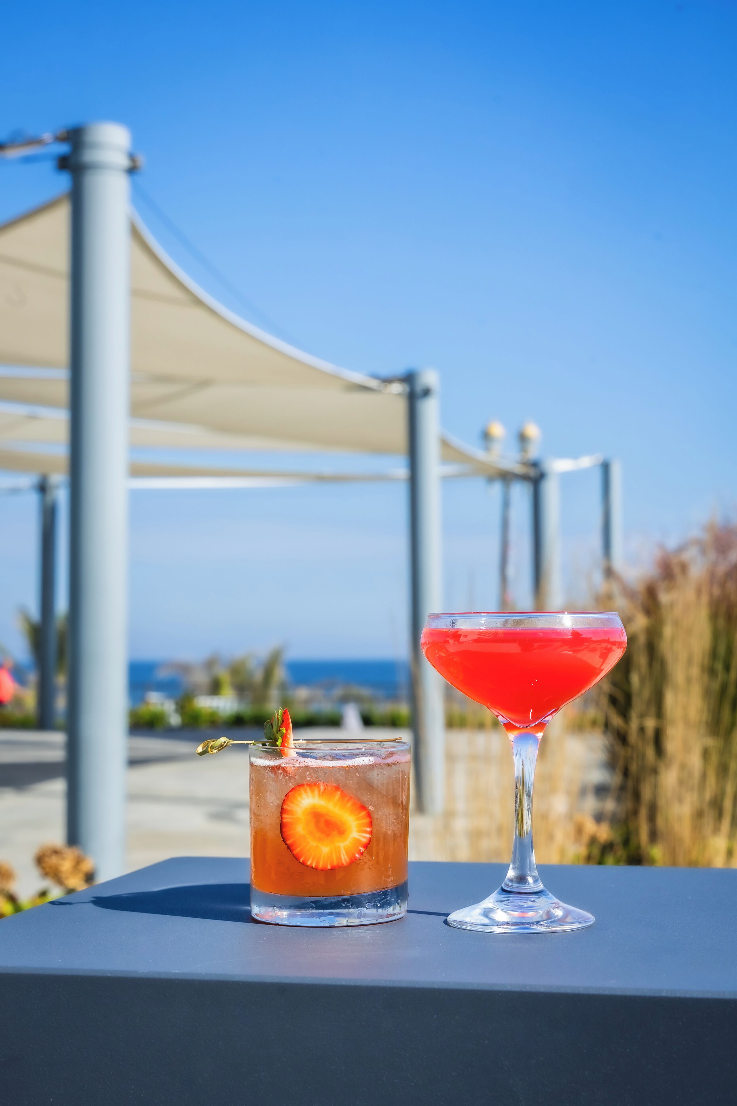 Deux boissons sur une table, avec un ciel dégagé et une structure visible en arrière-plan.