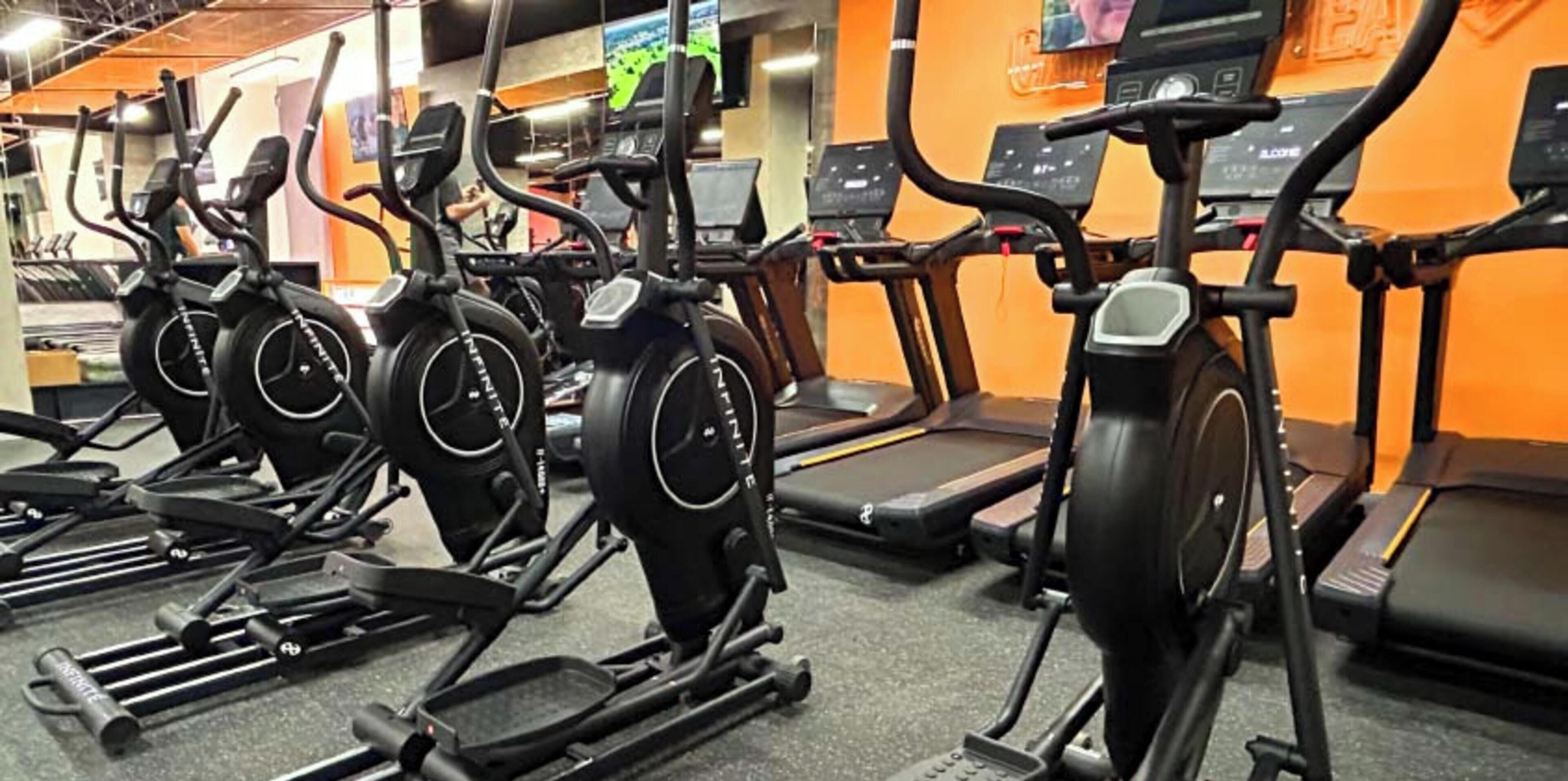 A row of stationary bikes and treadmills in a gym.