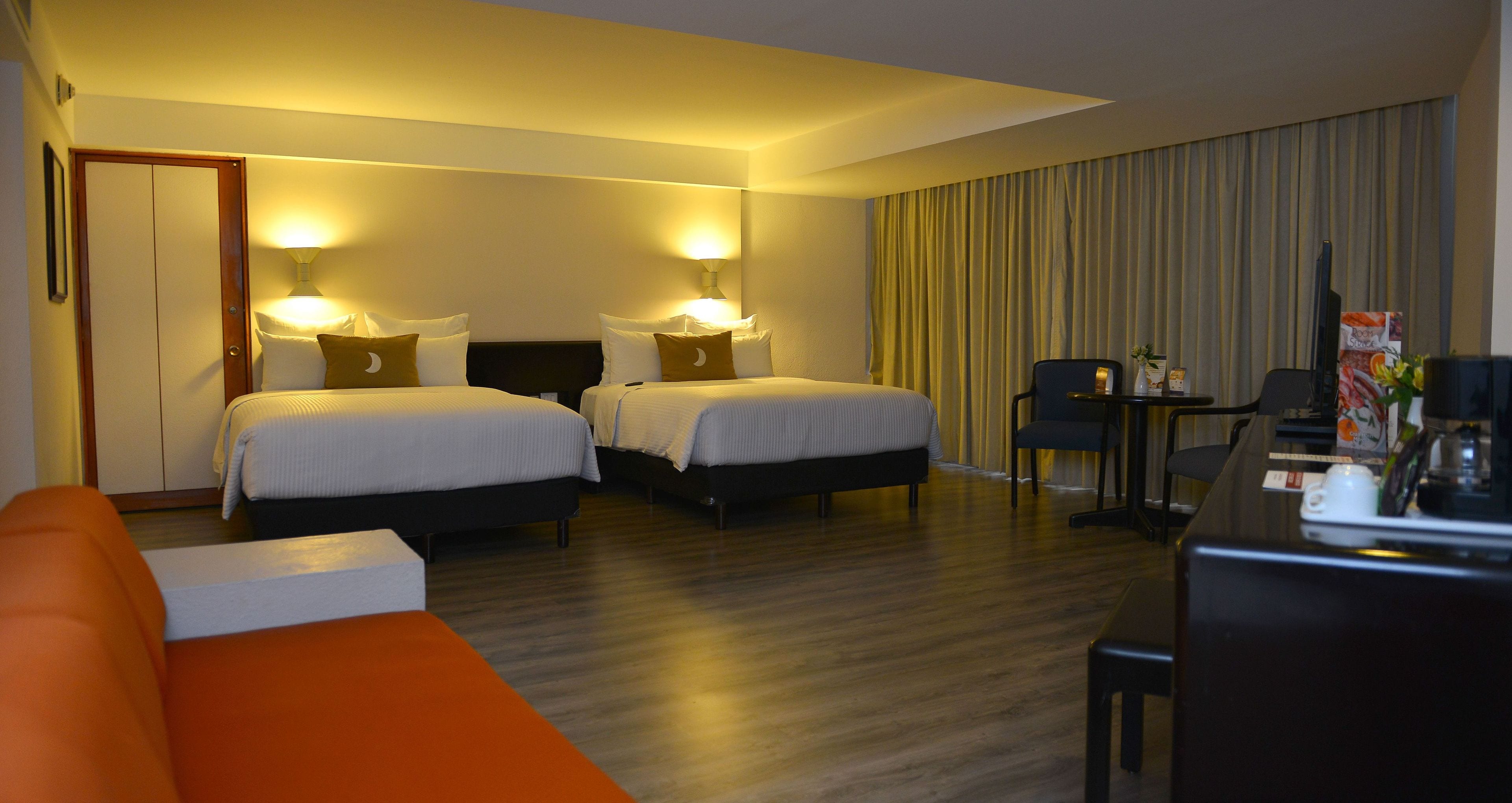 Habitación de hotel con dos camas, un escritorio, una silla y un sofá.