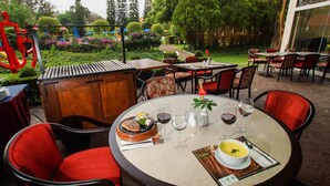 An outdoor dining area with round tables, red chairs, and a variety of dishes including a pie and soup. - Grand Cantalagua Hotel Morelia, BW Signature Collection (Morelia)