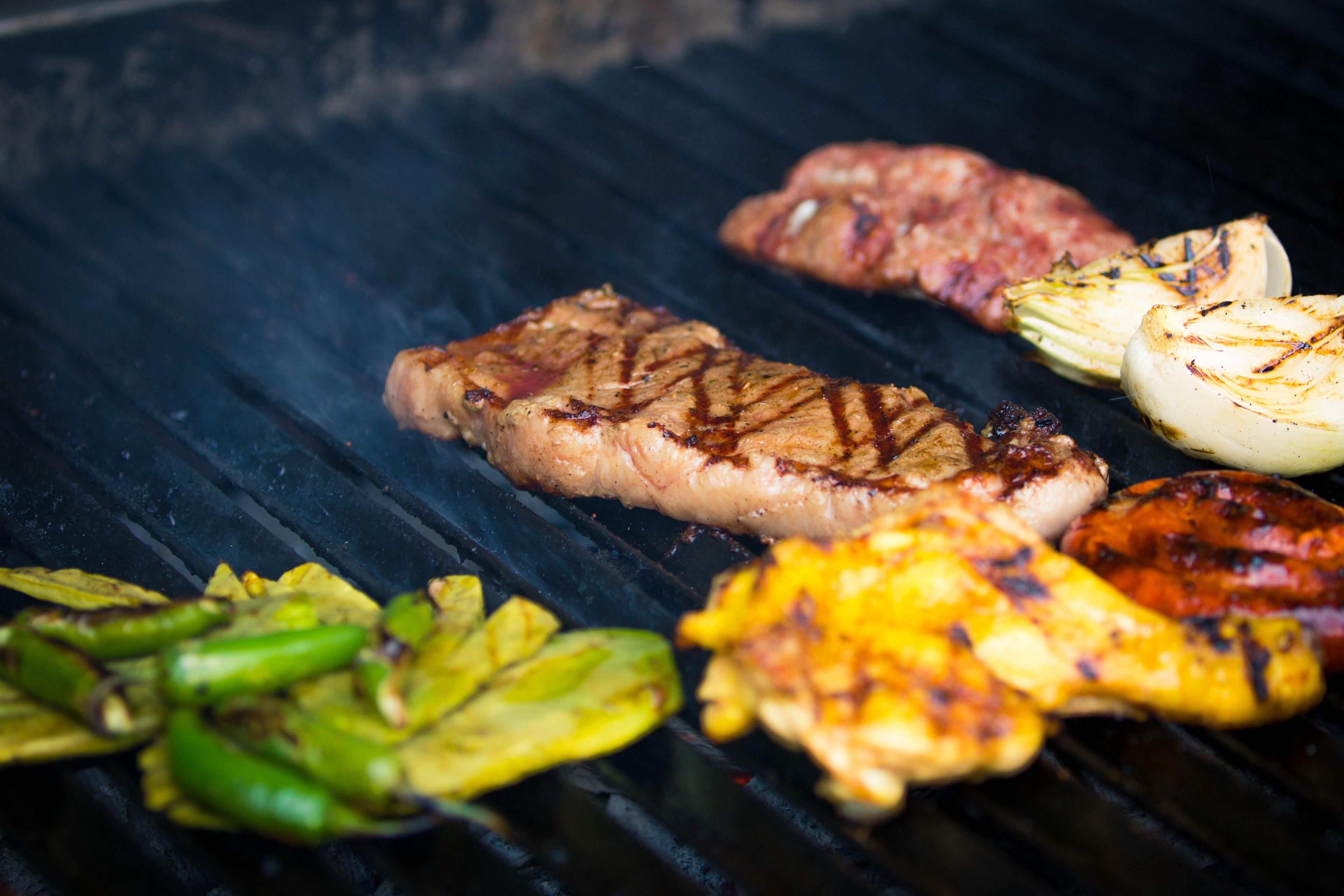 A grill with various meats and vegetables being cooked.