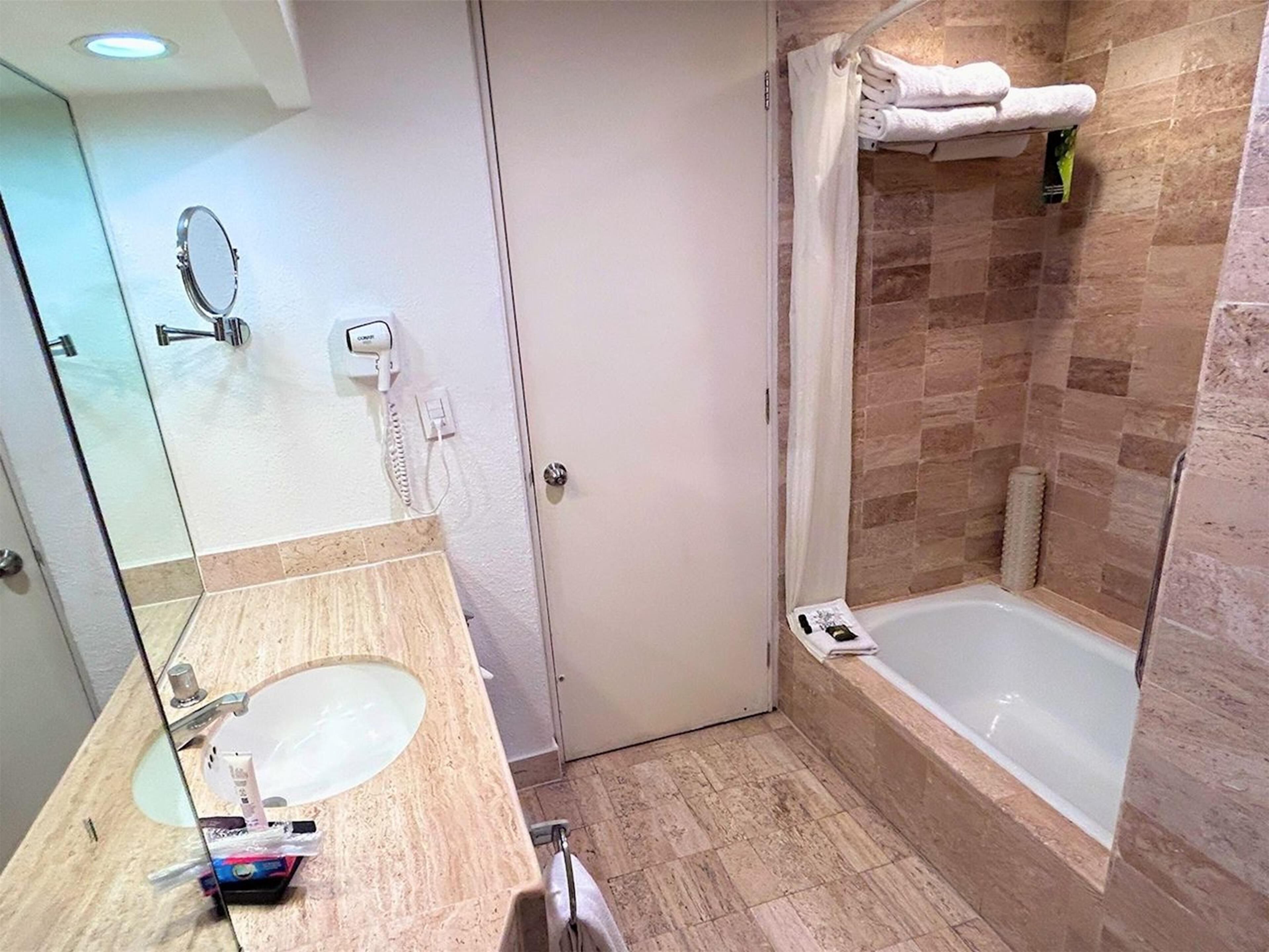 A bathroom with a sink, mirror, and shower area.