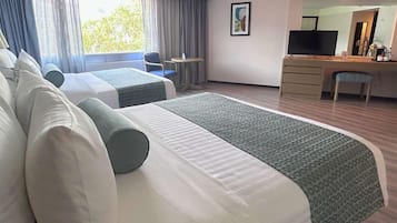 Une chambre d’hôtel avec deux lits, un bureau, une chaise, une télévision et une fenêtre avec des rideaux.