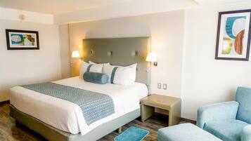 A hotel room with a large bed, two bedside tables, a chair, and artwork on the walls.