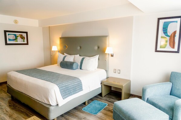 A hotel room with a large bed, two bedside tables, a chair, and artwork on the walls. - Grand Cantalagua Hotel Morelia, BW Signature Collection (Morelia)