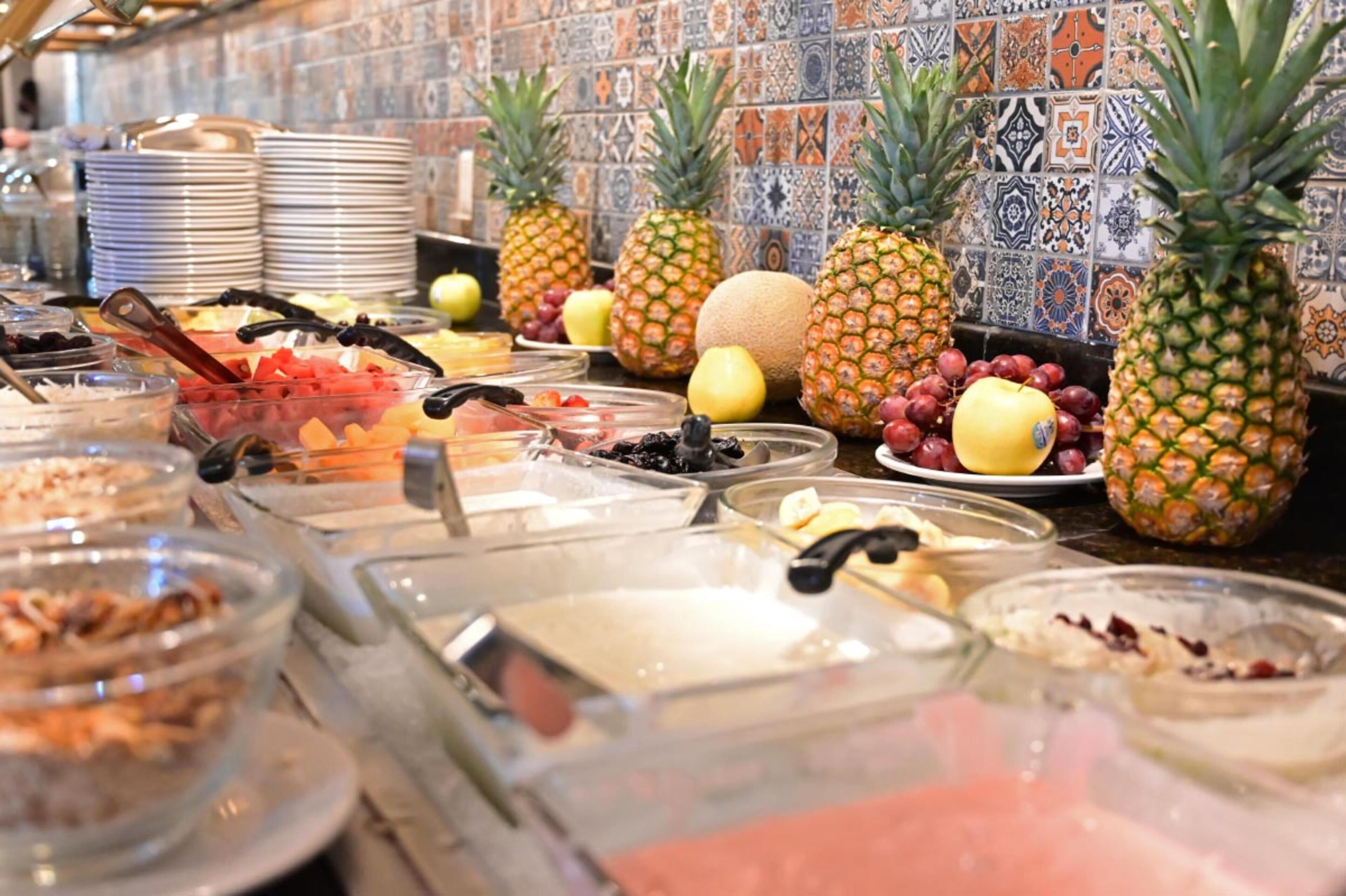 A buffet with various food items and tropical fruits like pineapples and melons.