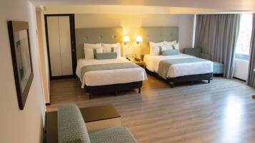 A hotel room with two beds, a sofa, and a small table.