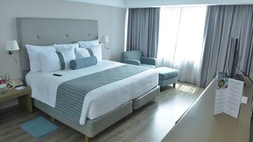A hotel room with a large bed, a desk with a phone, a chair, and a menu stand.