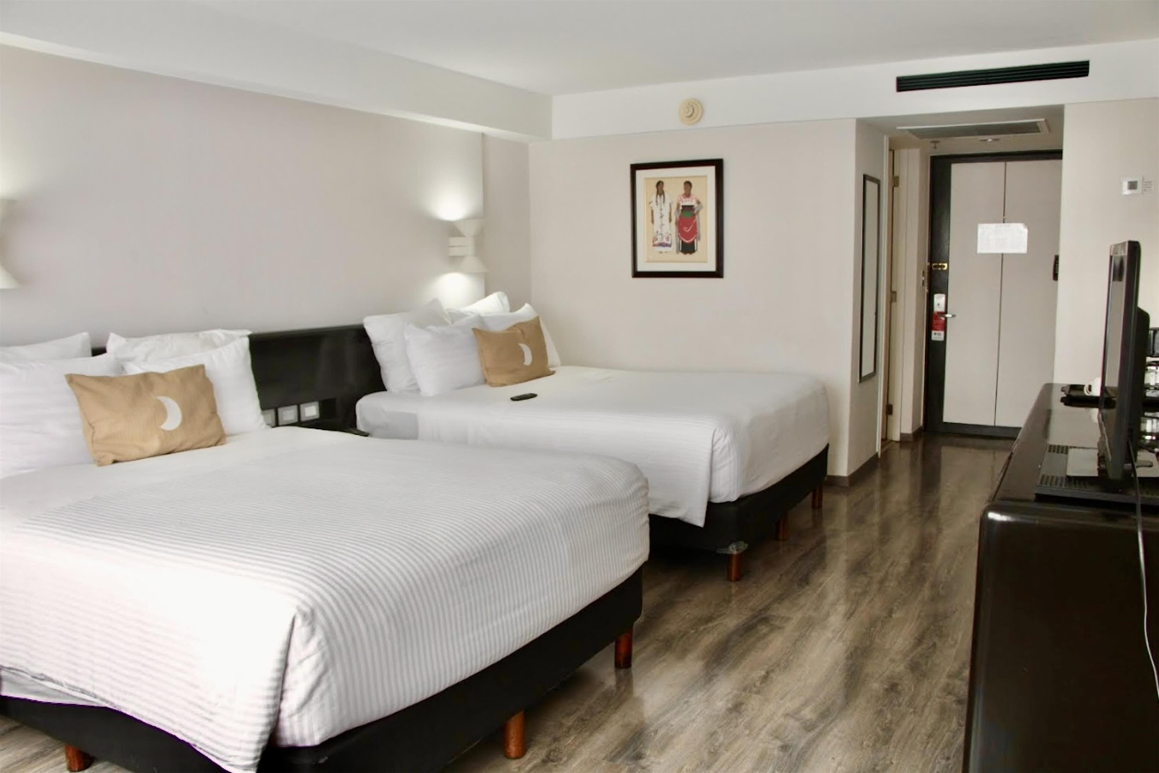 Une chambre d’hôtel avec deux lits, un bureau et une télévision.