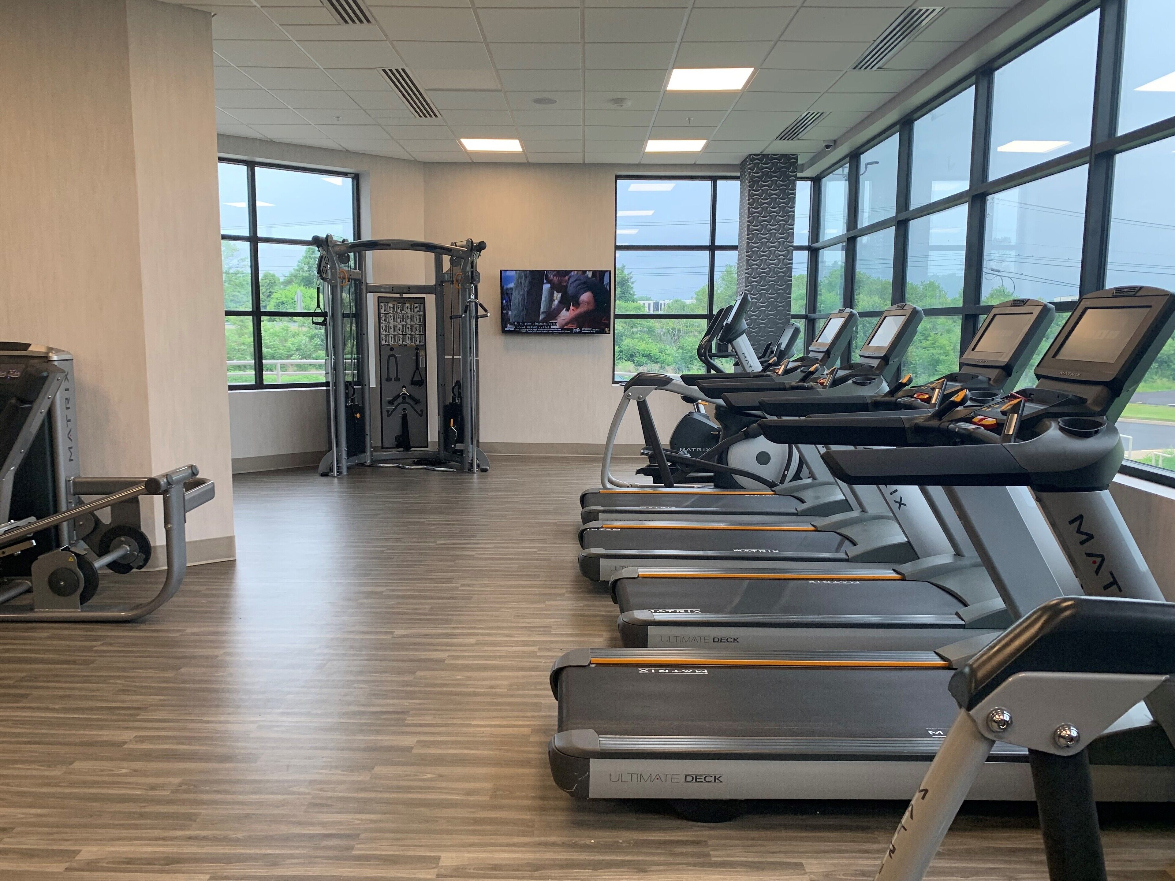 A gym with treadmills, a weight machine, and a TV screen.