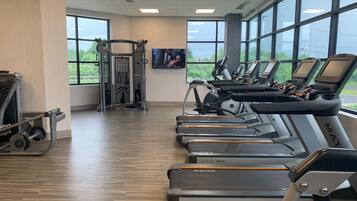 A gym with treadmills, a weight machine, and a TV screen.