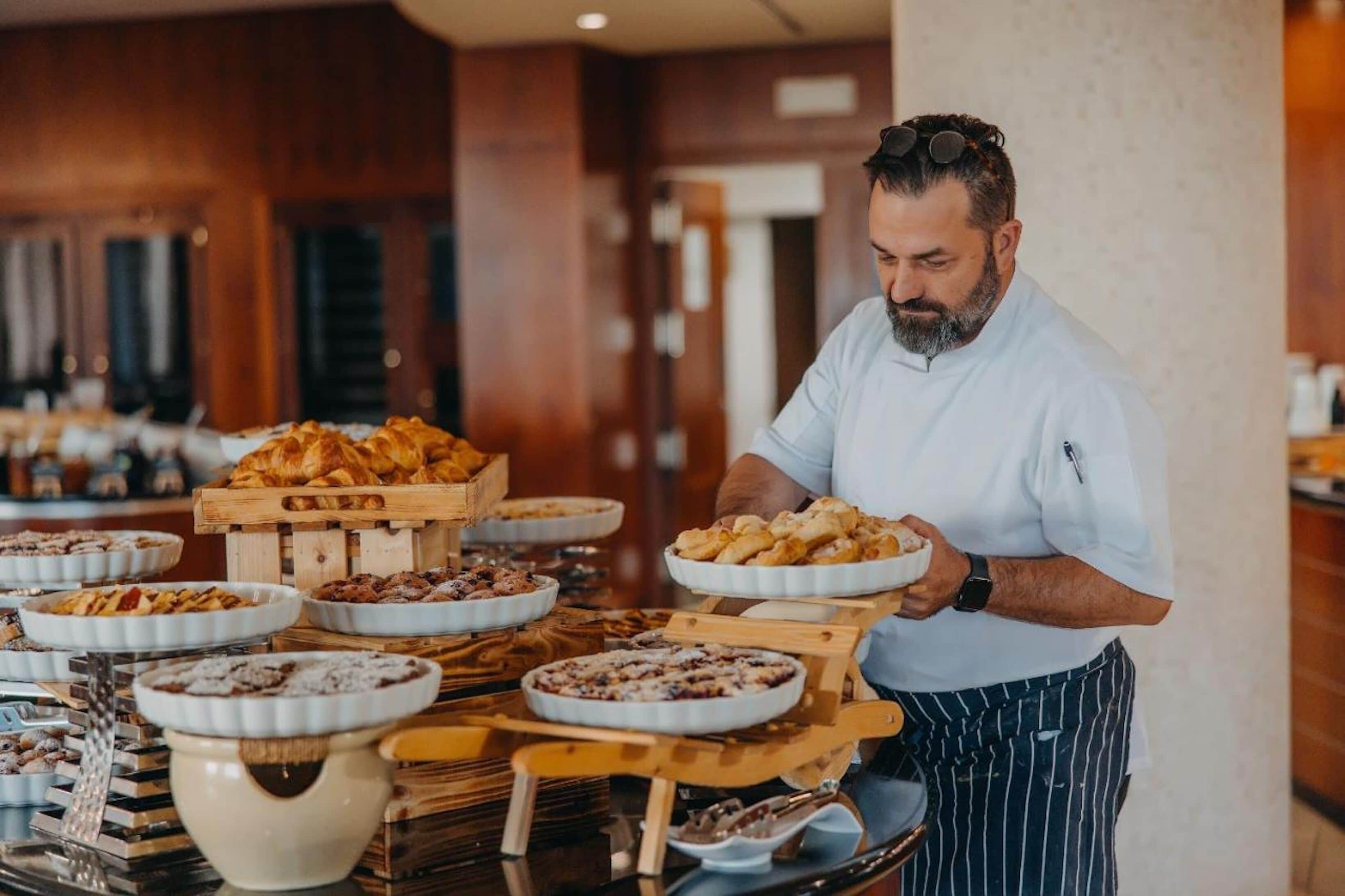 Een buffetopstelling met diverse gerechten en iemand die eten serveert.