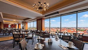 A restaurant with tables, chairs, and a view of a cityscape. - Grand Hotel Prague Towers (Prague)