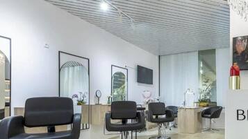 Ein moderner Friseursalon mit schwarzen Friseurstühlen, einer Rezeption und einem großen Gemälde an der Wand.