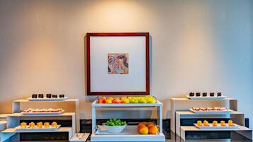 Montaje de bufé con diferentes alimentos y una obra de arte enmarcada en la pared.