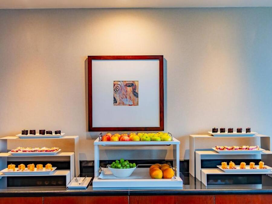 Montaje de bufé con diferentes alimentos y una obra de arte enmarcada en la pared.