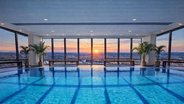 An indoor infinity pool with a cityscape view at sunset. - Grand Hotel Prague Towers (Prague)