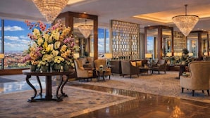 A spacious lobby with a large floral arrangement, comfortable seating, a bar area, and a city view. - Grand Hotel Prague Towers (Prague)