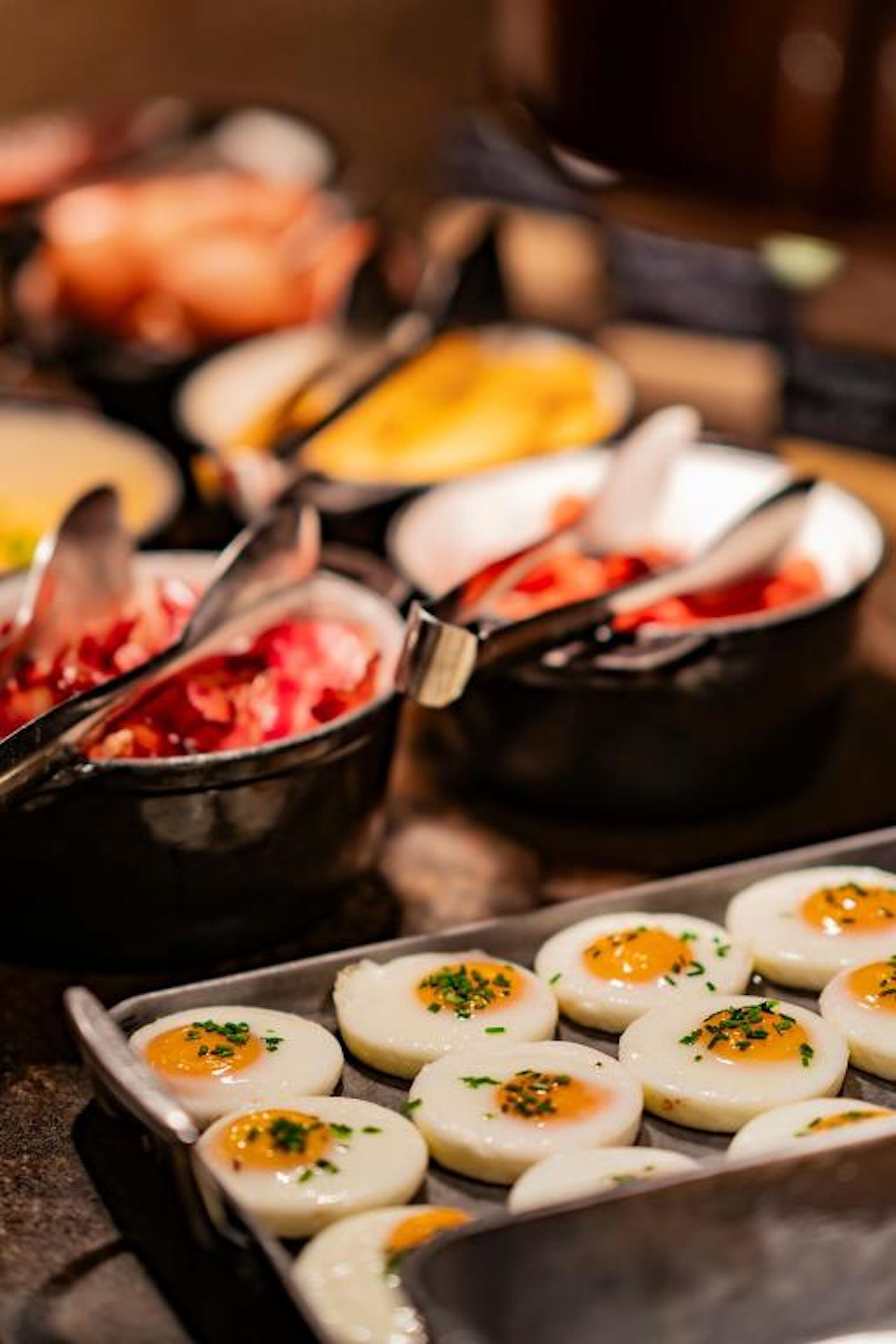 Variedad de platos, incluyendo una bandeja de huevos pochados adornados con hierbas, y varios cuencos de comida, probablemente con diferentes tipos de carne y verduras.