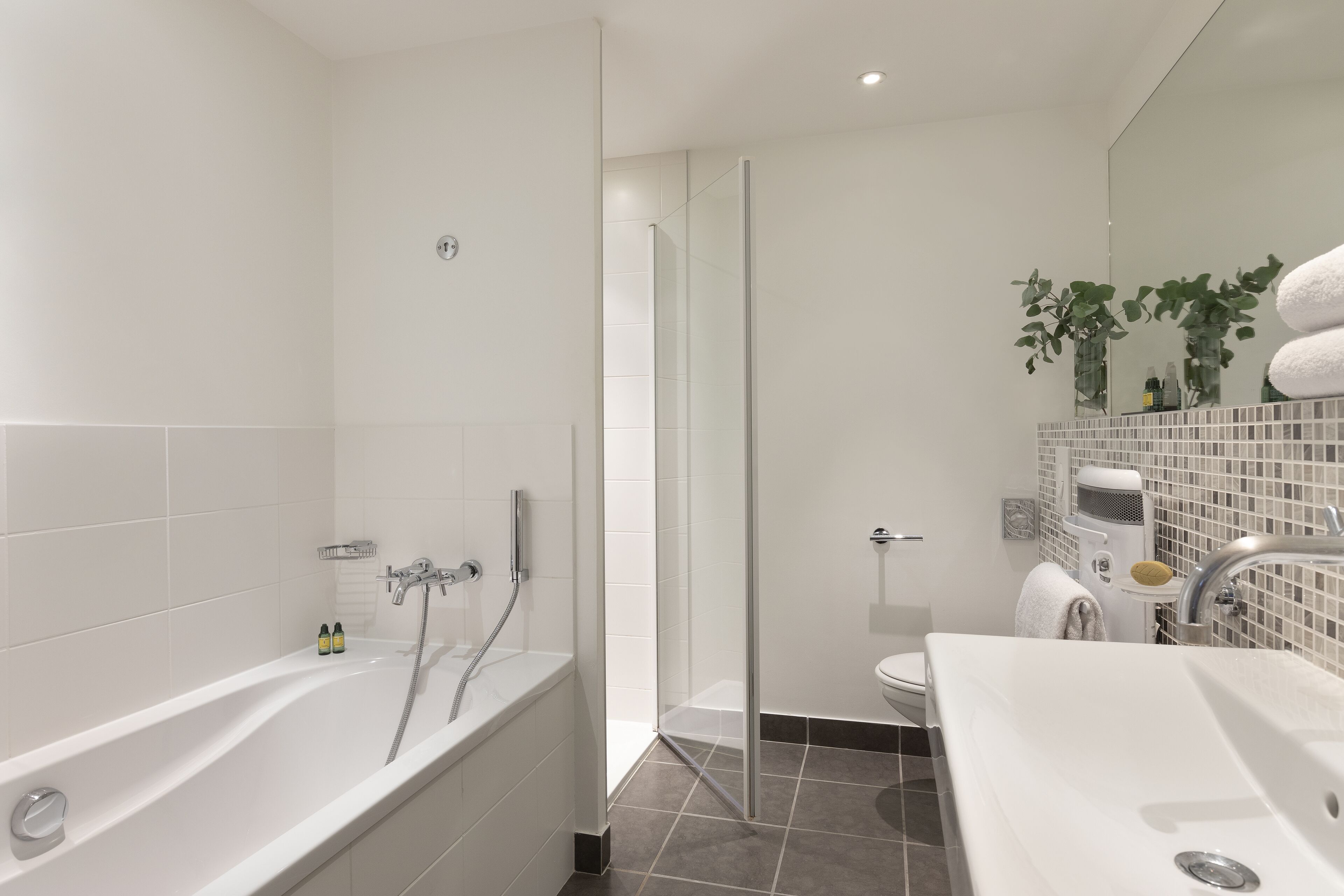 A modern bathroom with a bathtub, shower, and sink.