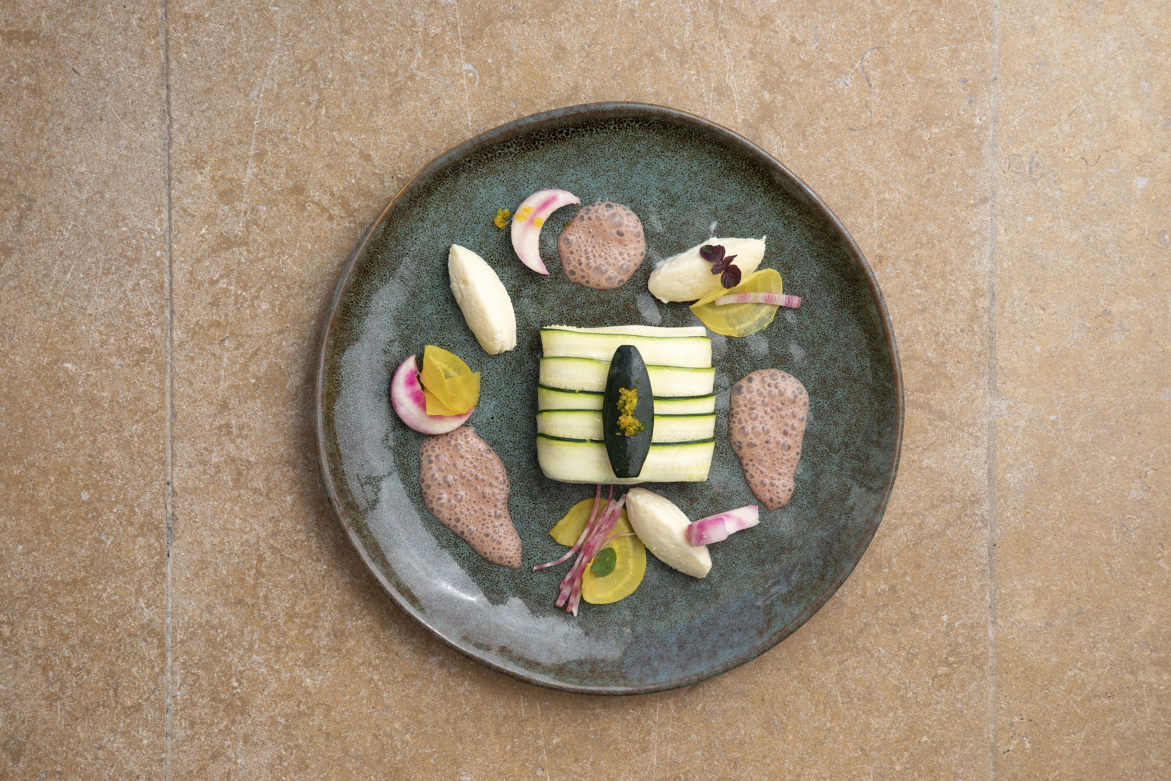 Une assiette contenant divers aliments, notamment des tranches de concombre, un morceau de viande et quelques légumes.