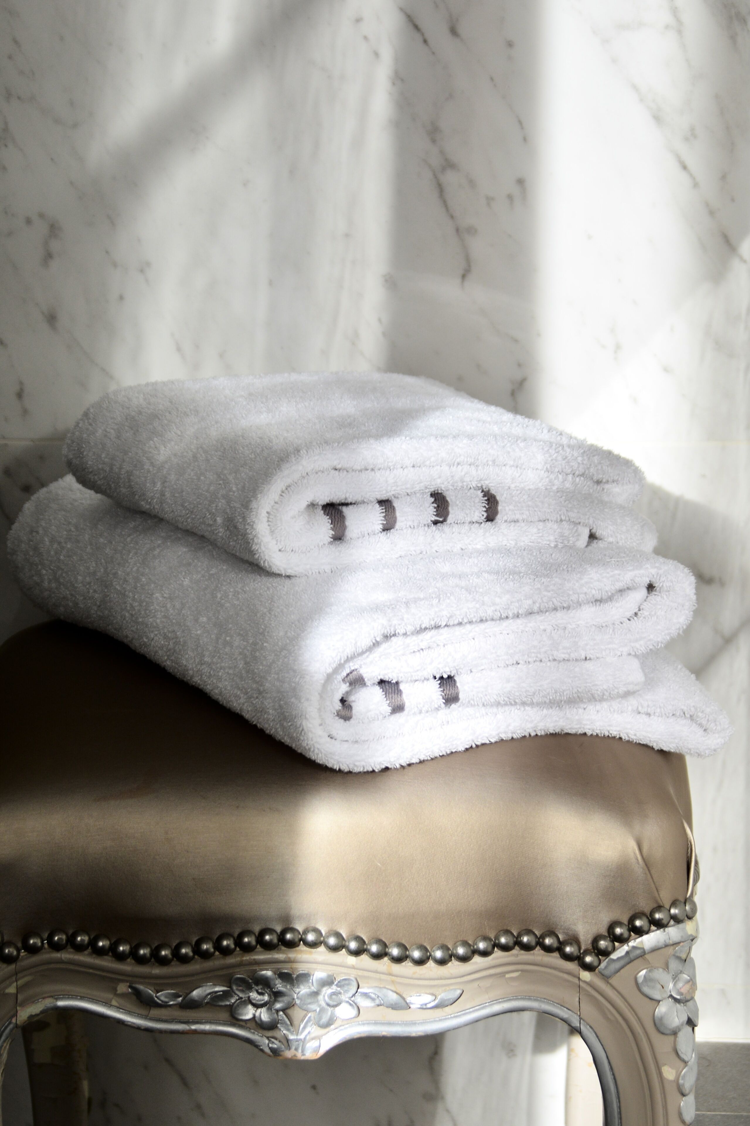 A stack of white towels on a metallic bench with a decorative edge.