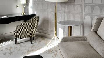 Una sala de estar moderna con un sofá, un sillón estampado, una mesita y una lámpara de pie.