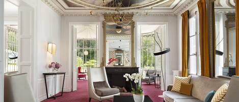 Una habitación lujosa con chimenea, muebles elegantes y una araña.
