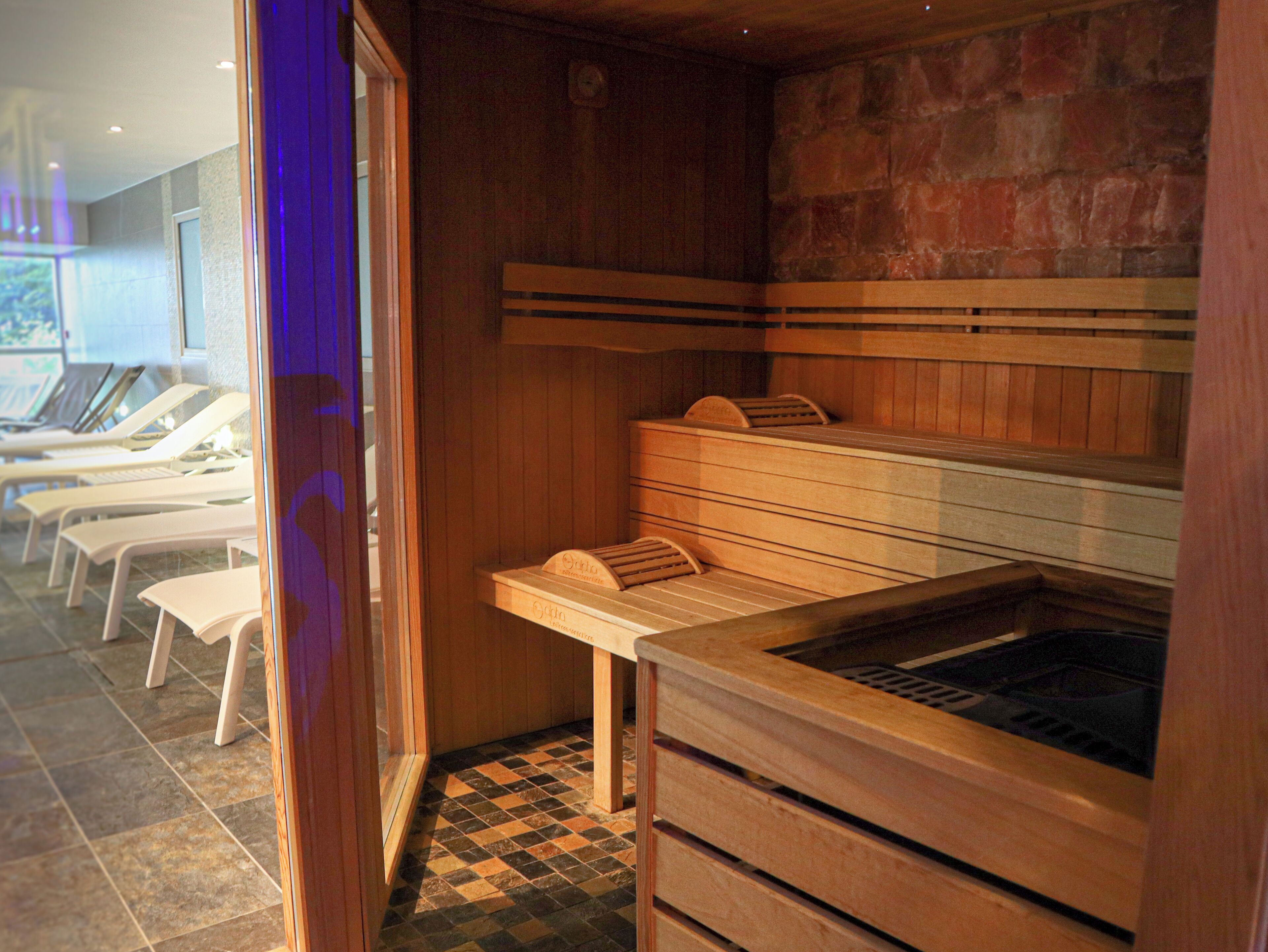 A sauna room with wooden benches and a stone wall.