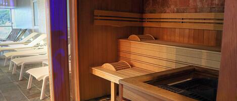 A sauna room with wooden benches and a stone wall.
