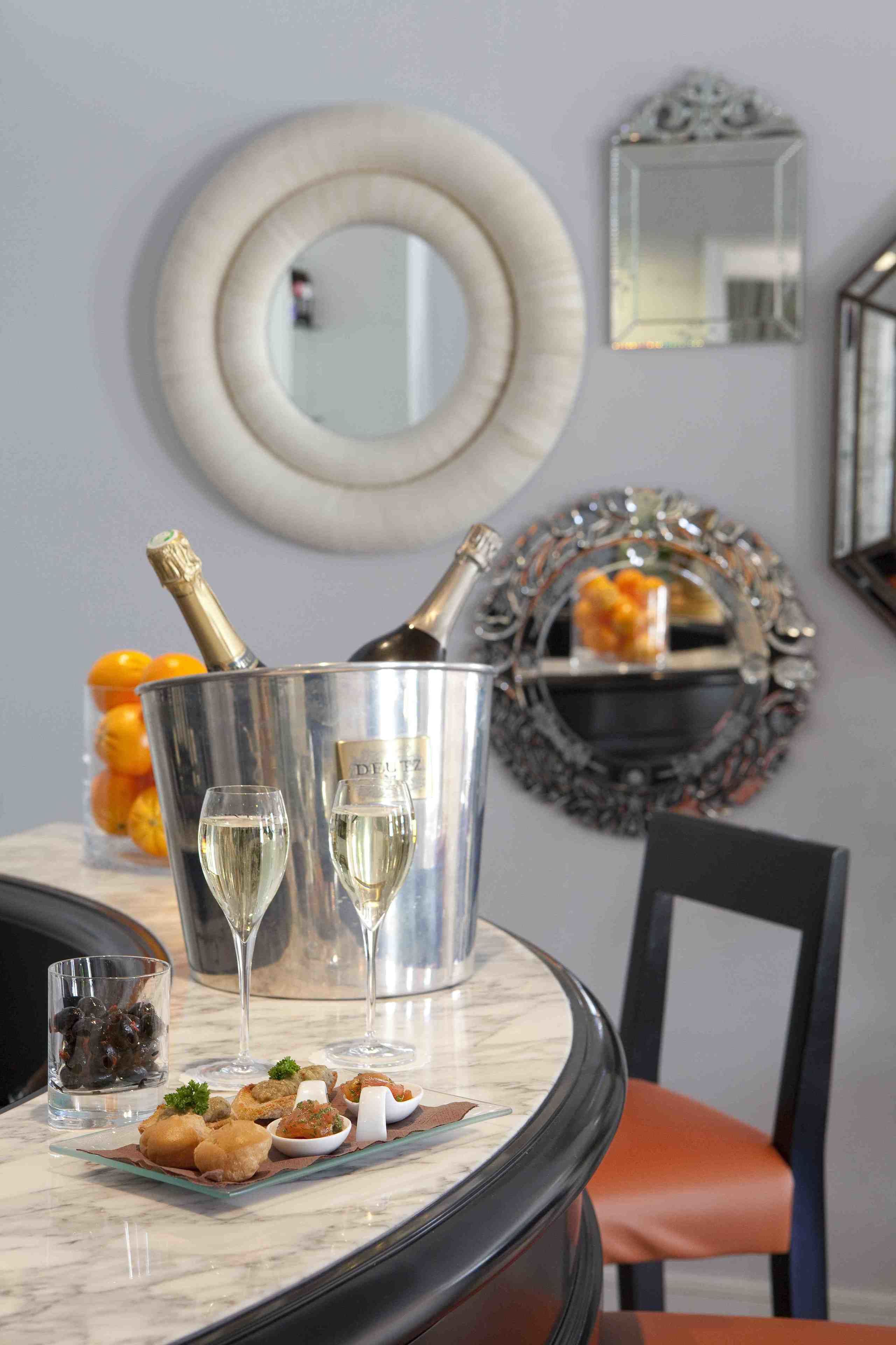 Un tavolo da pranzo con un secchiello per champagne, due bicchieri e un piatto di antipasti.