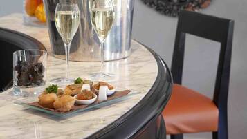 A dining table with a champagne bucket, two glasses, and a plate of appetizers.