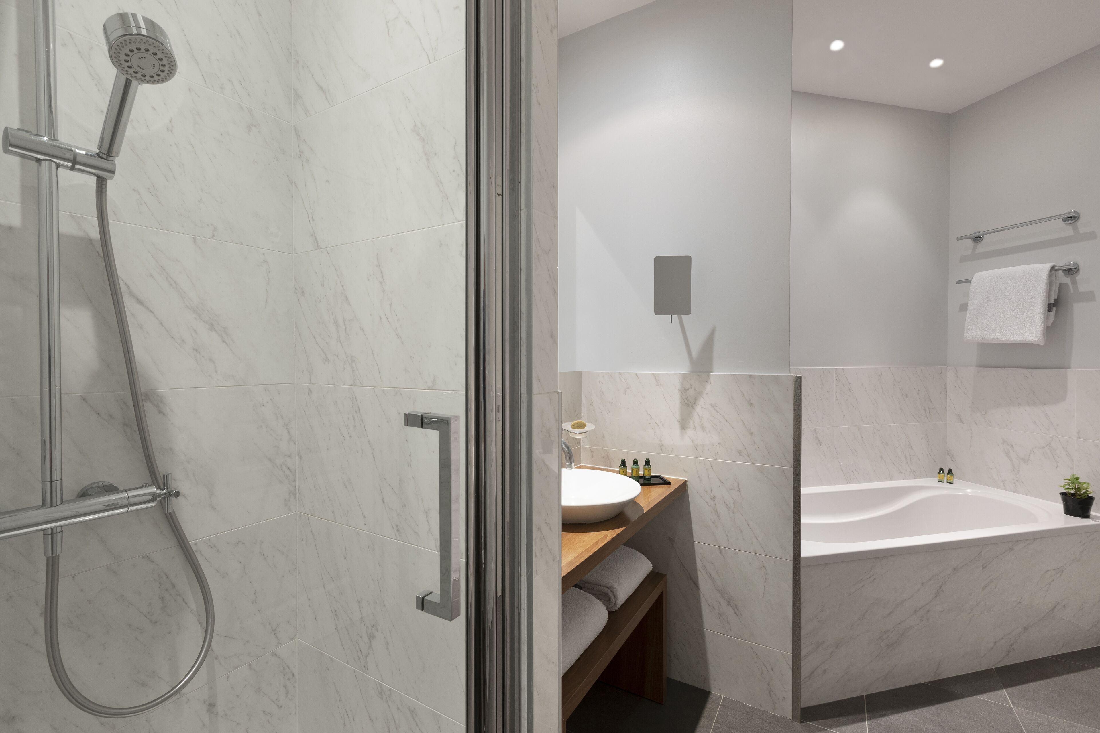 A modern bathroom with a glass-enclosed shower, a freestanding bathtub, and a vanity with a sink and mirror.