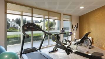 A gym with a treadmill, stationary bike, and rowing machine.